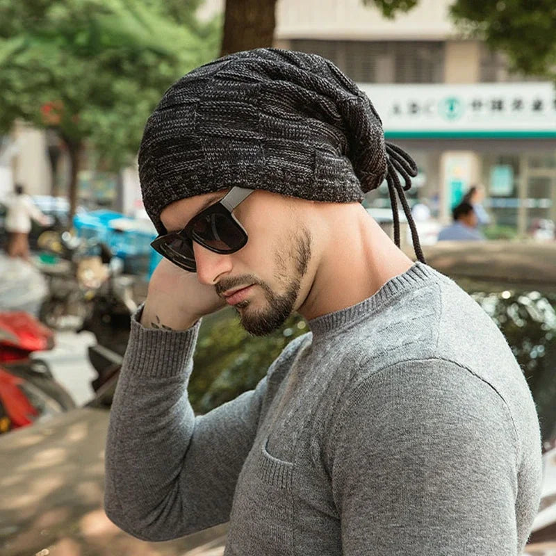 Man wearing a gray knit beanie and sunglasses with a blurred urban background