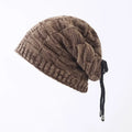 Brown knitted beanie with a drawstring on a light gray background
