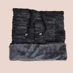 Folded black knit beanie scarf with fur trim on a beige background
