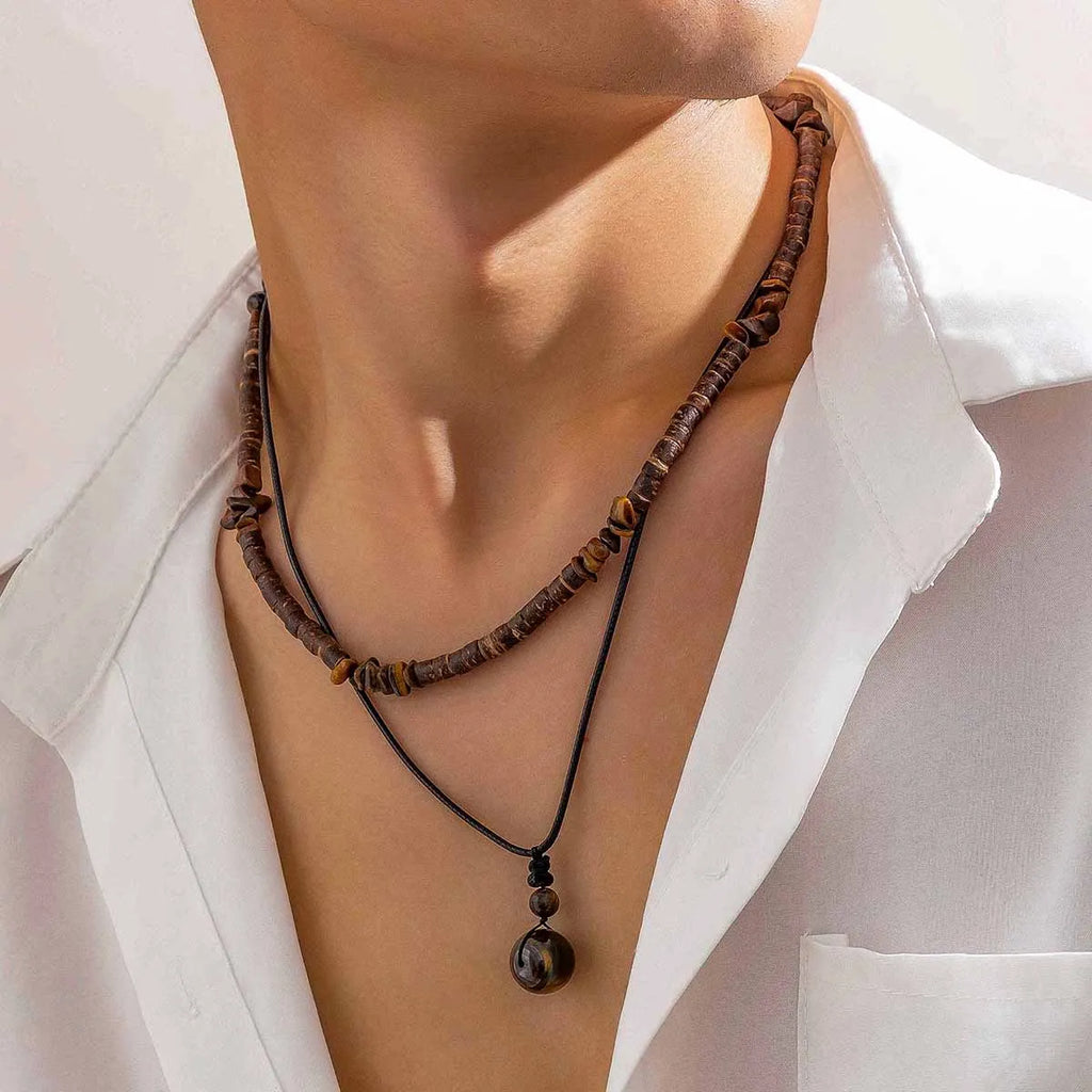 Necklace with brown beads worn by a person in a white shirt