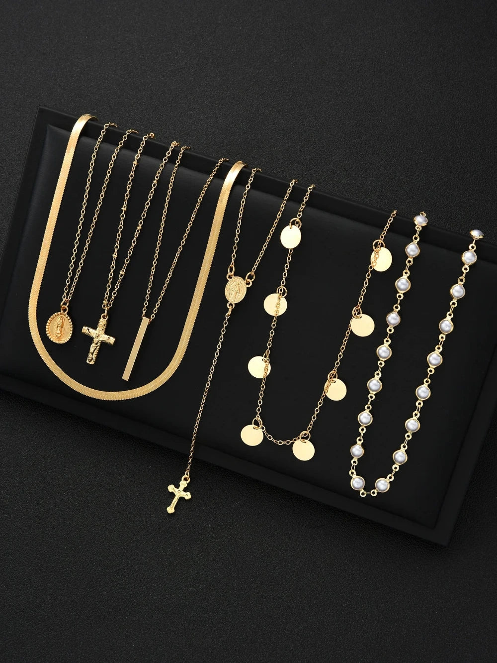 Set of gold necklaces with various designs on a black background