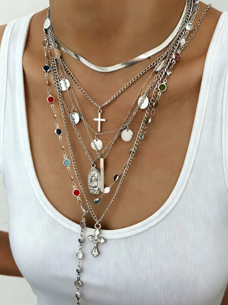 Multiple necklaces with various pendants on a white tank top