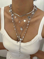 Necklace with multiple layers and various pendants on a white top