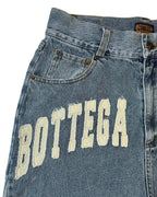 Close-up of a denim jeans jorts with 'Bottega' branding on a white background