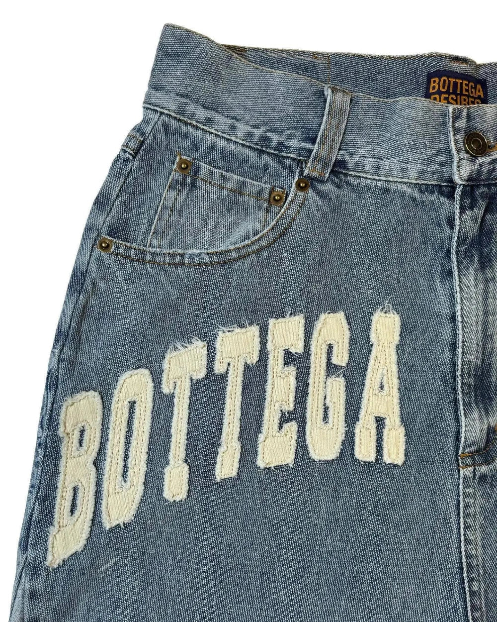 Close-up of a denim jeans jorts with 'Bottega' branding on a white background
