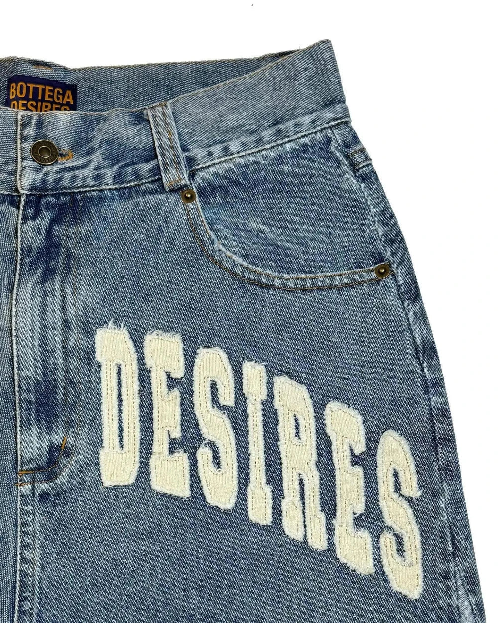 Blue vintage denim jeans with 'DESIRES' text and Bottega Veneta label.