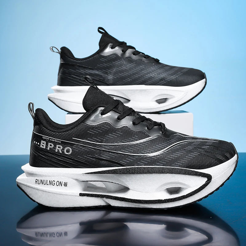 A pair of black and white athletic sneakers with a textured mesh upper and thick cushioned soles, displayed on a reflective surface against a light blue background.