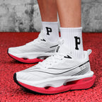 White sneakers with red soles worn on a red surface