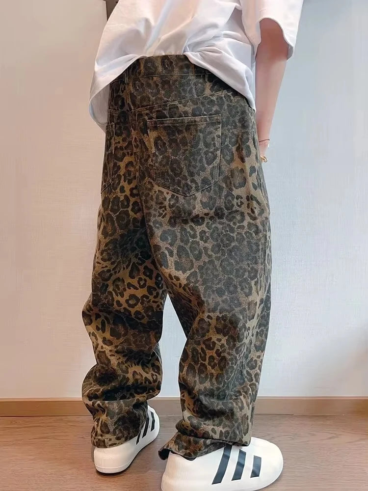 Person wearing leopard print pants and white sneakers on a plain background