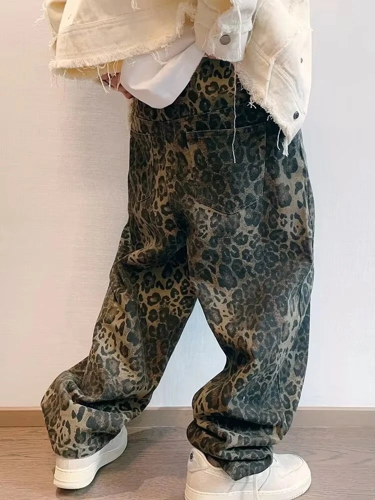 Person wearing leopard print pants with a white jacket and shoes on a plain background