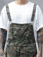 Person wearing a white t-shirt with 'Berlin' text and camouflage overalls.