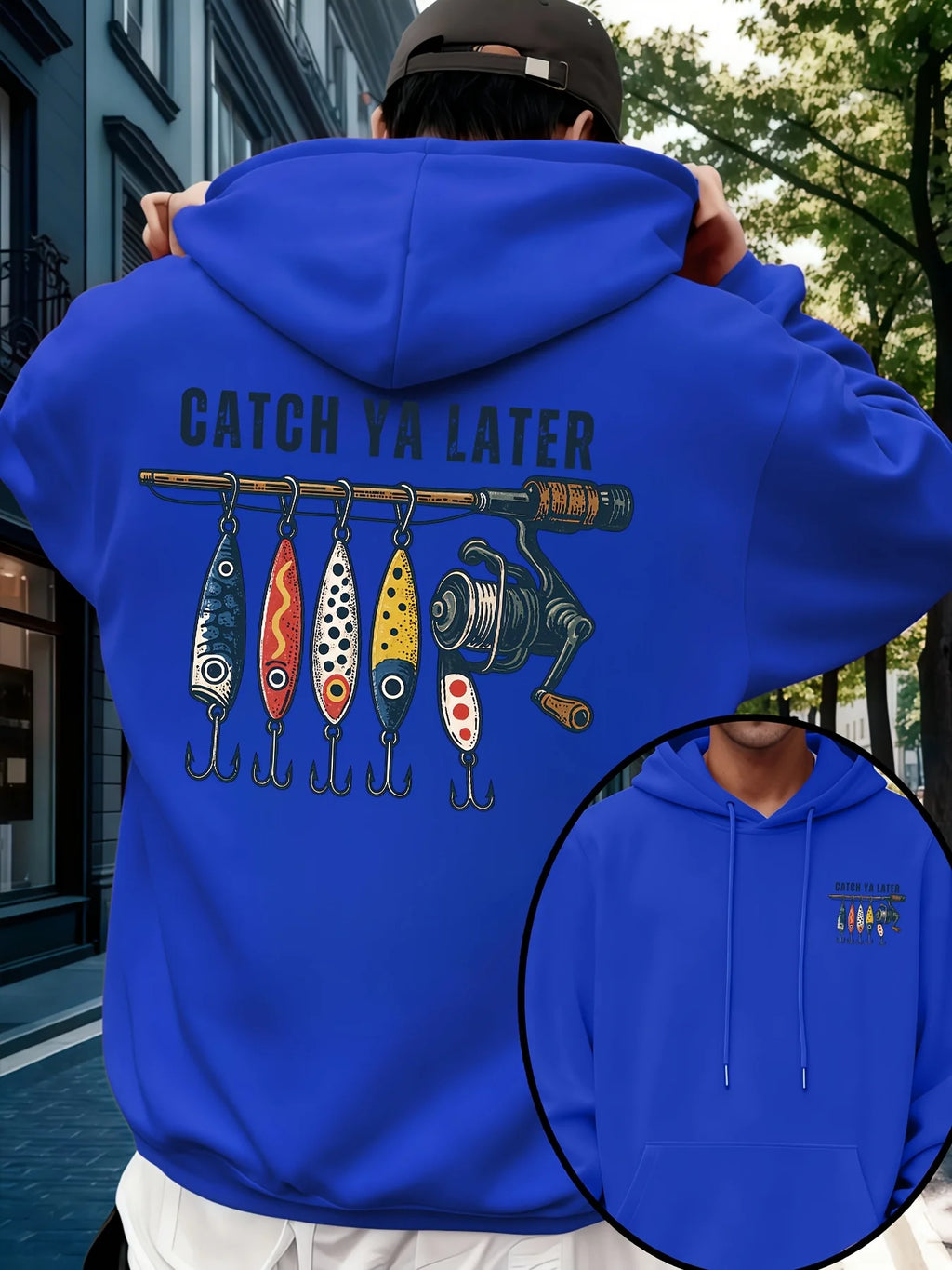 A person outdoors wearing a bright royal blue hoodie, shown from the back. The hoodie has a large fishing-themed graphic with the text 'CATCH YA LATER' above four colorful fishing lures and a fishing rod.