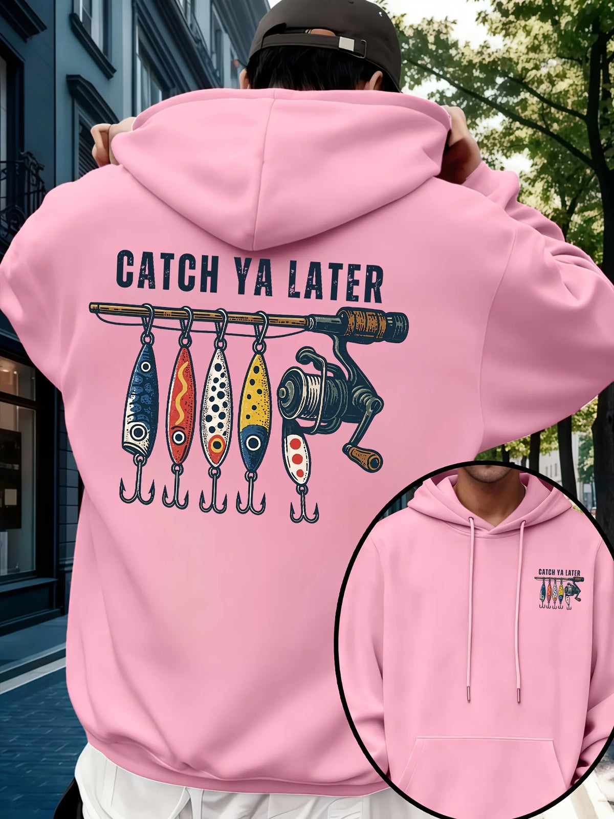 A person outdoors wearing a light pink hoodie, shown from the back. The hoodie has a large graphic print featuring the text 'CATCH YA LATER' above a fishing lure and reel illustration.