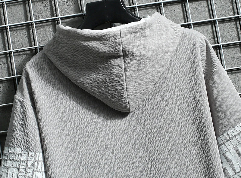 Gray hoodie with text on sleeves against a grid background