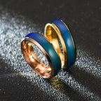Two rings with blue and gold bands on a textured black background