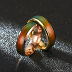 Three interlocking rings in gold, rose gold, and green on a textured black background