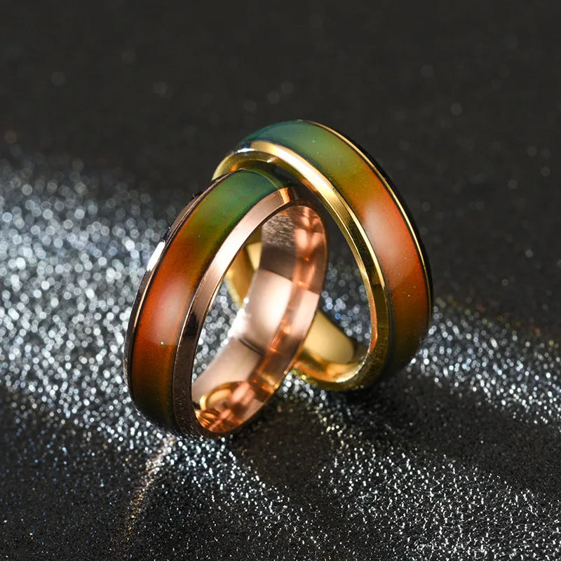 Three interlocking rings in gold, rose gold, and green on a textured black background