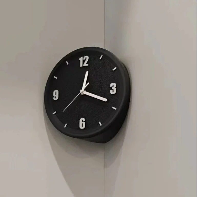 A minimalist black round wall clock with white numerals and hands, mounted on a light gray corner wall.