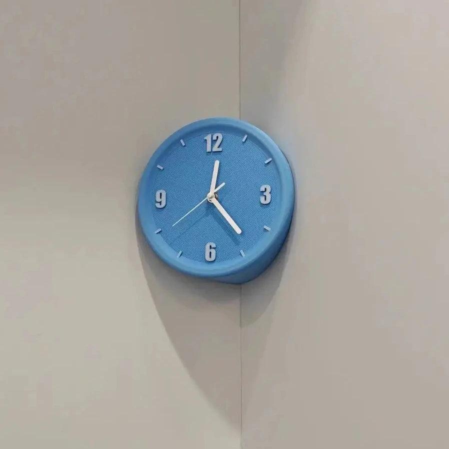 A round blue wall clock with white numerals and hands, mounted on a light beige corner wall.