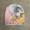 Colorful beanie with gothic anime-style design on a concrete surface
