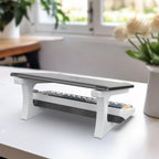 Keyboard riser on a desk with a laptop and keyboard, in a bright room with plants.