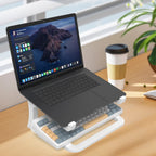 Laptop on a stand with a keyboard and mouse on a desk, next to a coffee cup and plant.