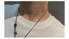 Person wearing a white shirt with a silver chain necklace