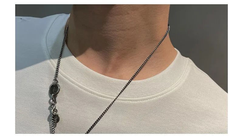Person wearing a white shirt with a silver chain necklace