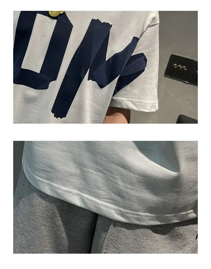 White t-shirt with navy blue lettering and gray pants on a neutral background