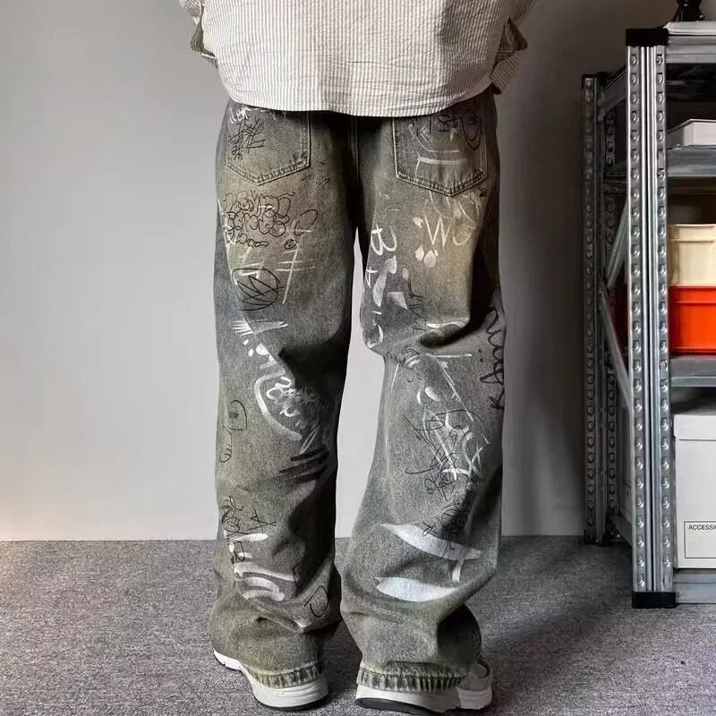 Person wearing gray jeans with graffiti-style text in a room with a shelf in the background.