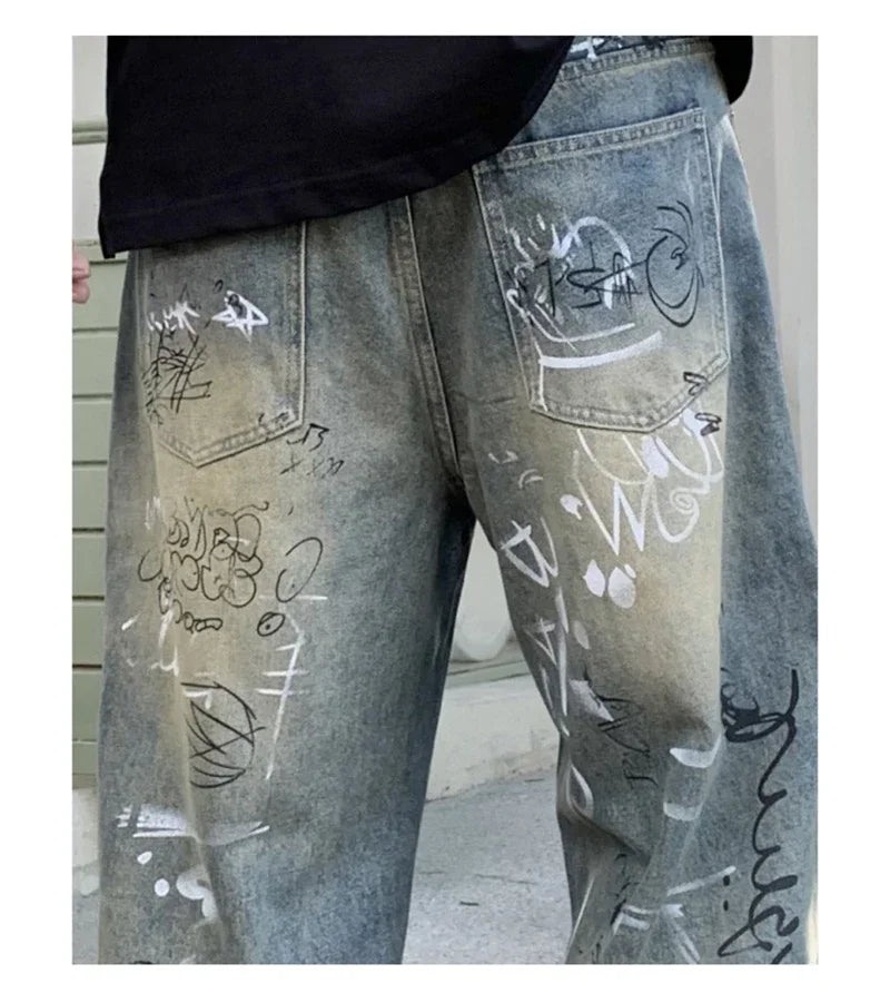 Gray jeans with white and black graffiti-style writing on a plain background
