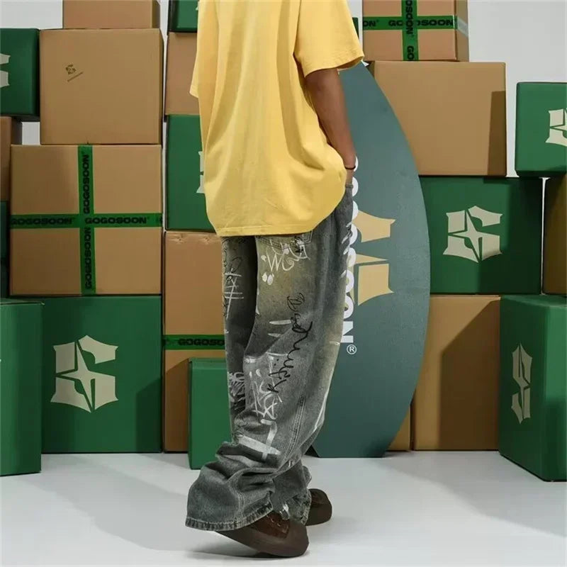 Person wearing a yellow shirt and gray pants standing in front of stacked boxes with a visible brand logo.