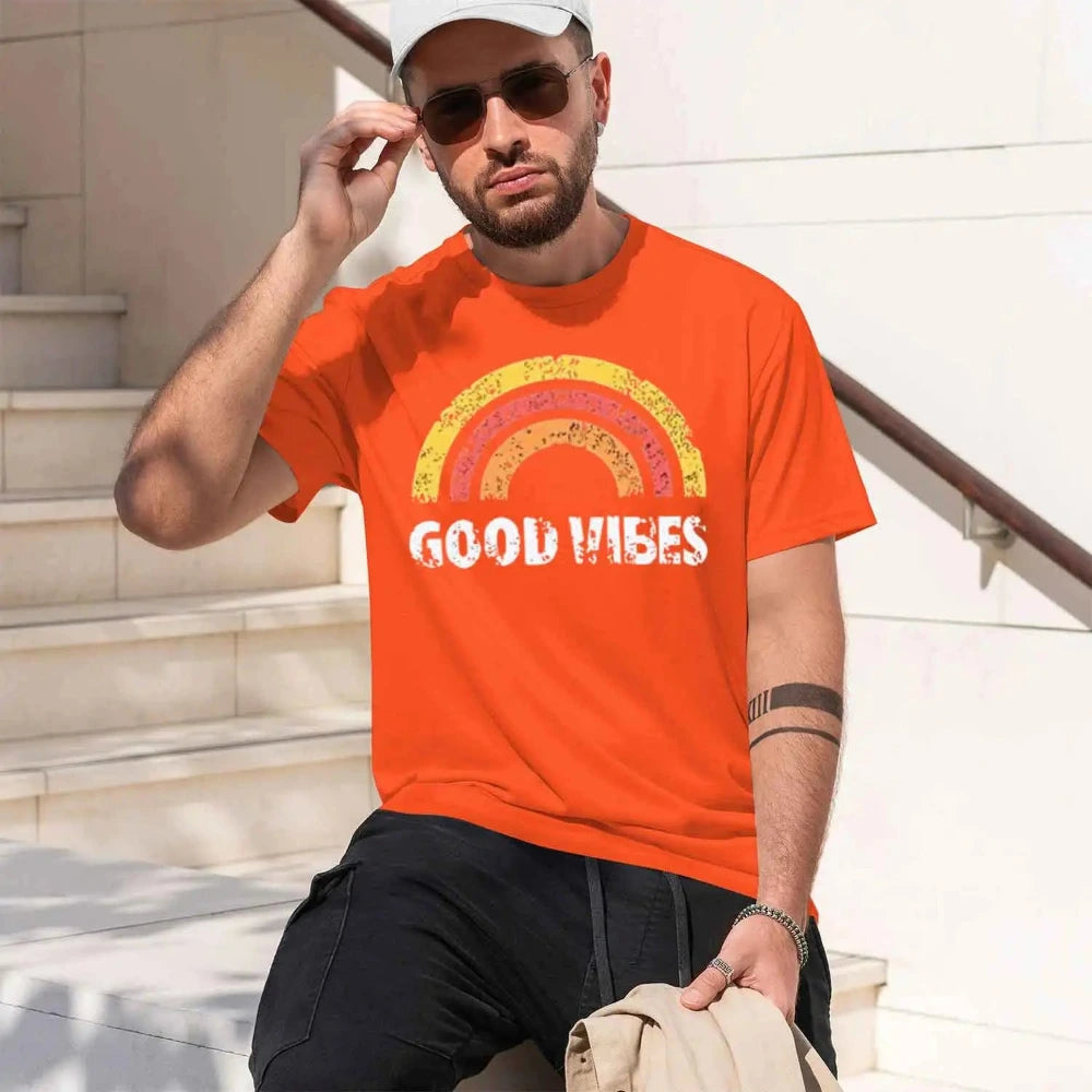 A man wearing an orange t-shirt with a retro rainbow graphic and the words 'GOOD VIBES'.