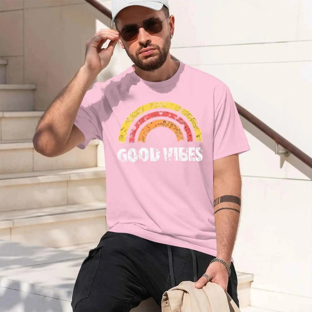 Man wearing a pink t-shirt with 'GOOD VIBES' printed on it, sitting outdoors.