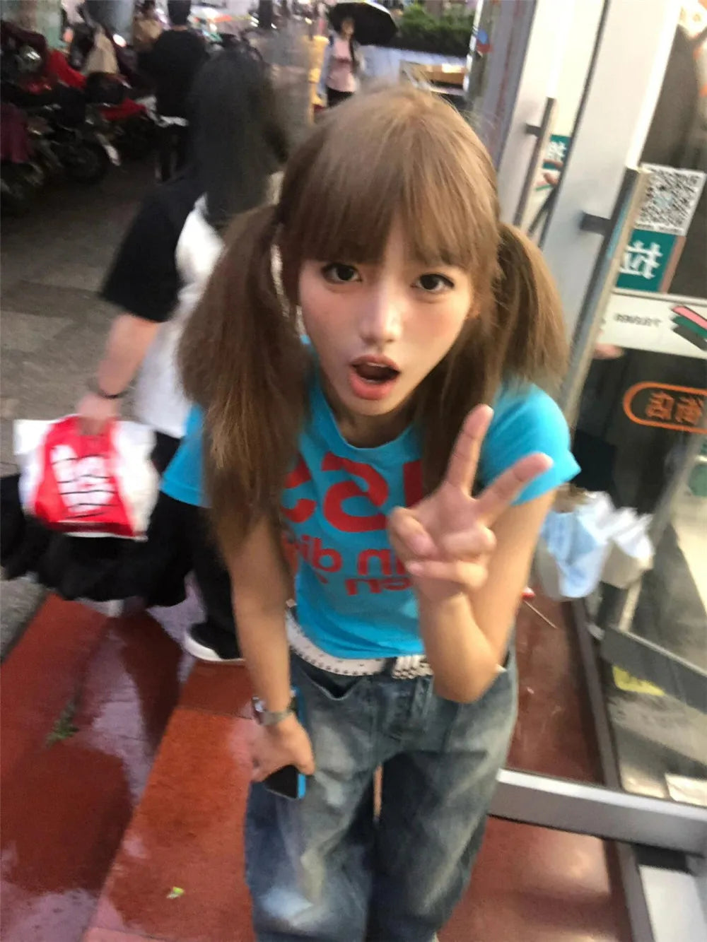 Person making a peace sign in an urban setting wearing a Kiss T-shirt Fashion Vintage Harajuku Streetwear blue