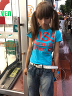 Woman wearing a Kiss T-shirt Fashion Vintage Harajuku Streetwear standing on a wet sidewalk.