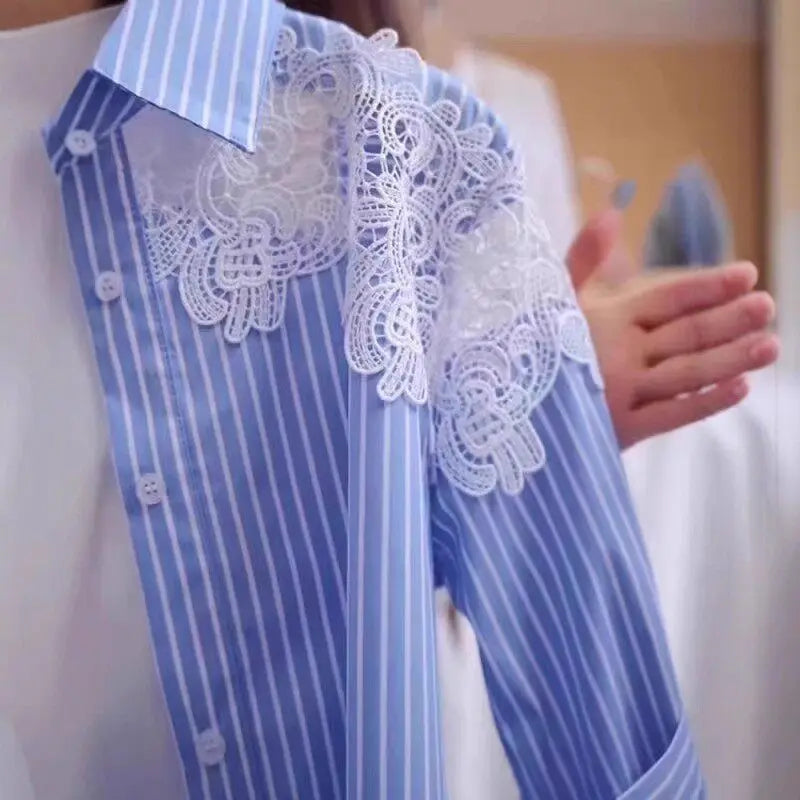 A close-up of a blue and white striped long-sleeve shirt with a large white lace applique detail across the chest, worn by a person whose hand is visible gesturing near the shoulder.