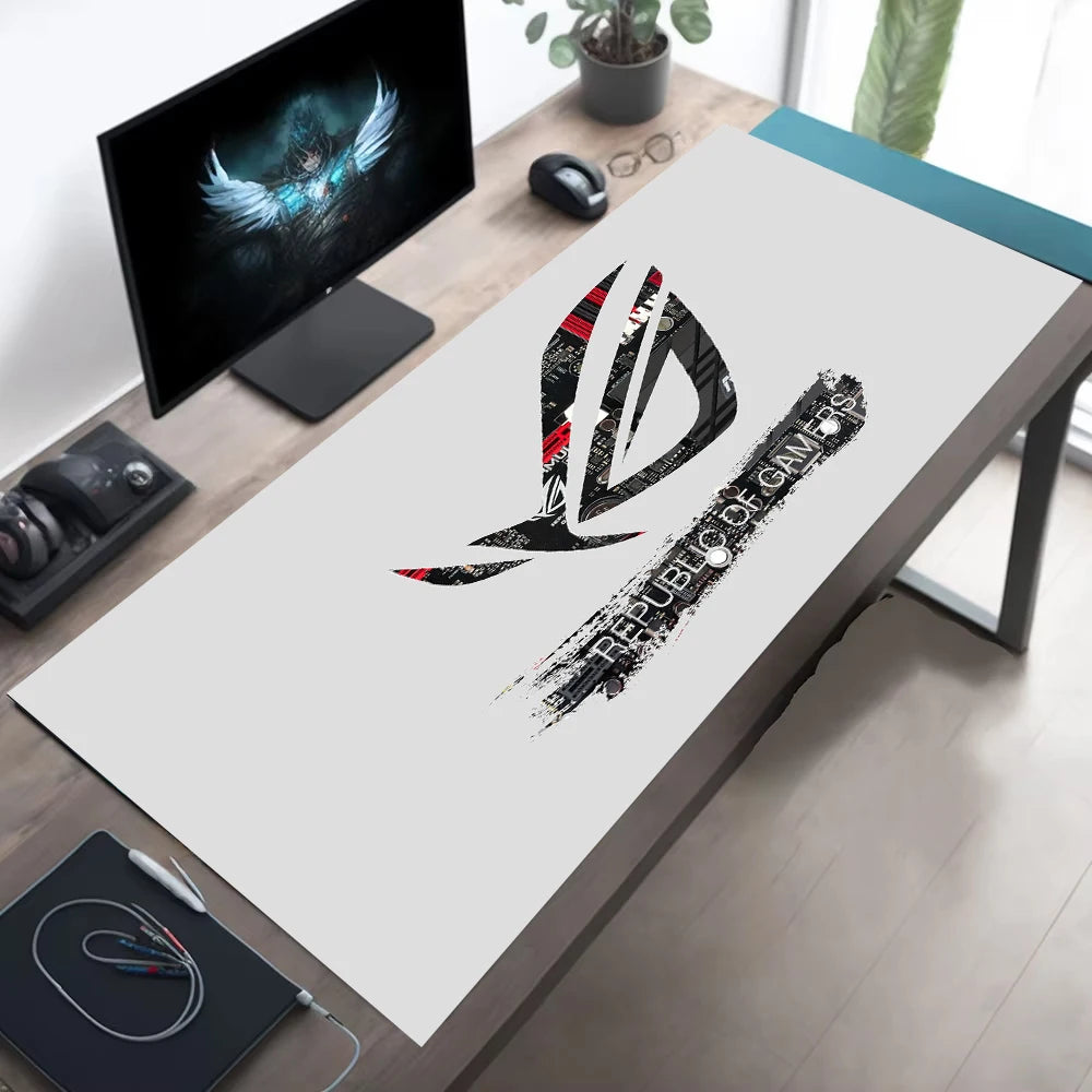 A large white desk mat featuring a black and red Republic of Gamers logo, laid out on a wooden desk in a modern home office setup.