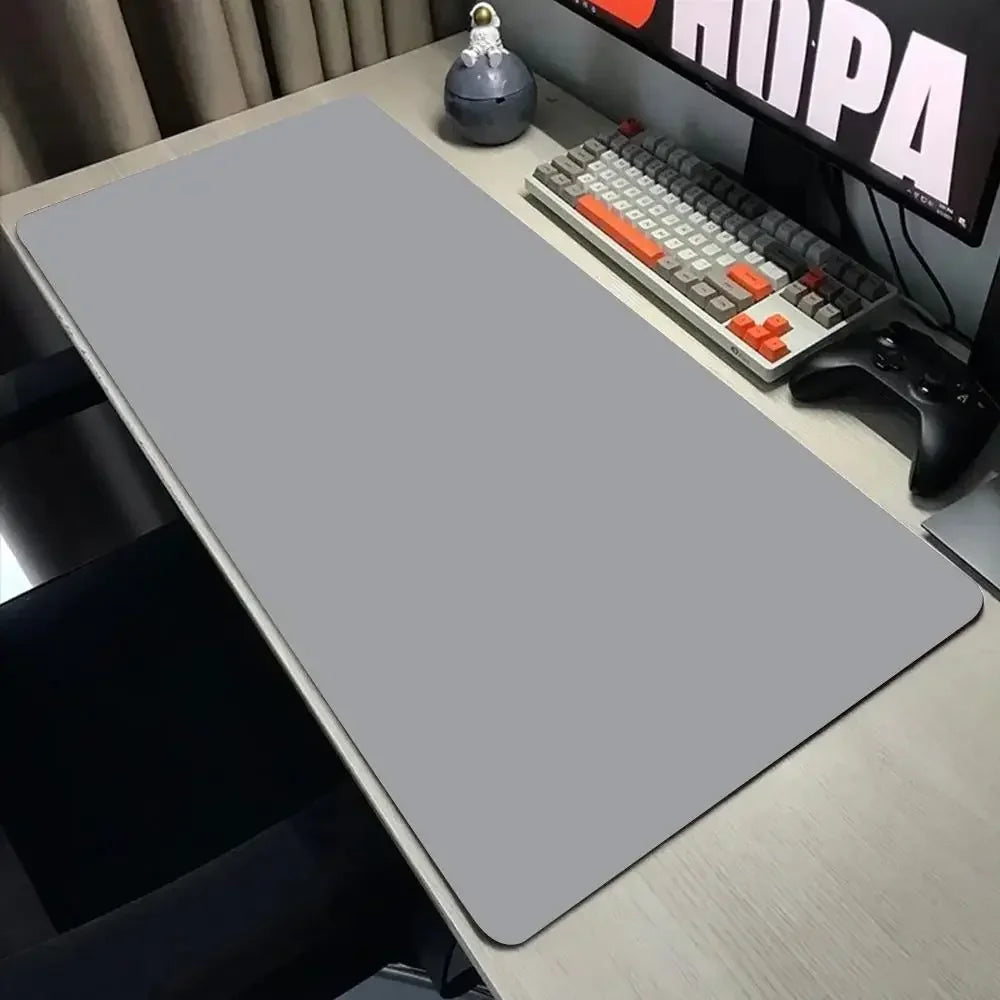 Gray desk mat on a desk with a keyboard and monitor in the background