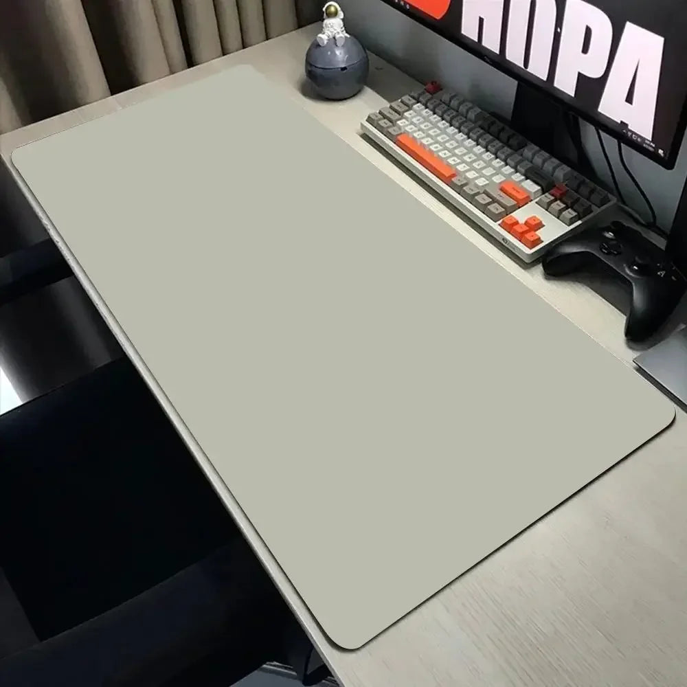 Desk setup with a large desk mat, keyboard, and monitor on a wooden desk.