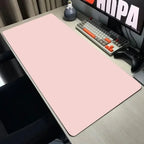 Pink desk mat on a desk with a keyboard and monitor in the background