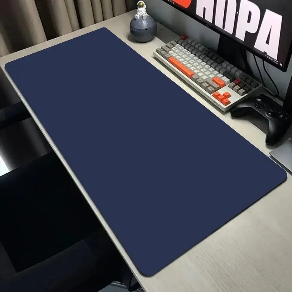 Blue mouse pad on a desk with a keyboard and monitor in the background