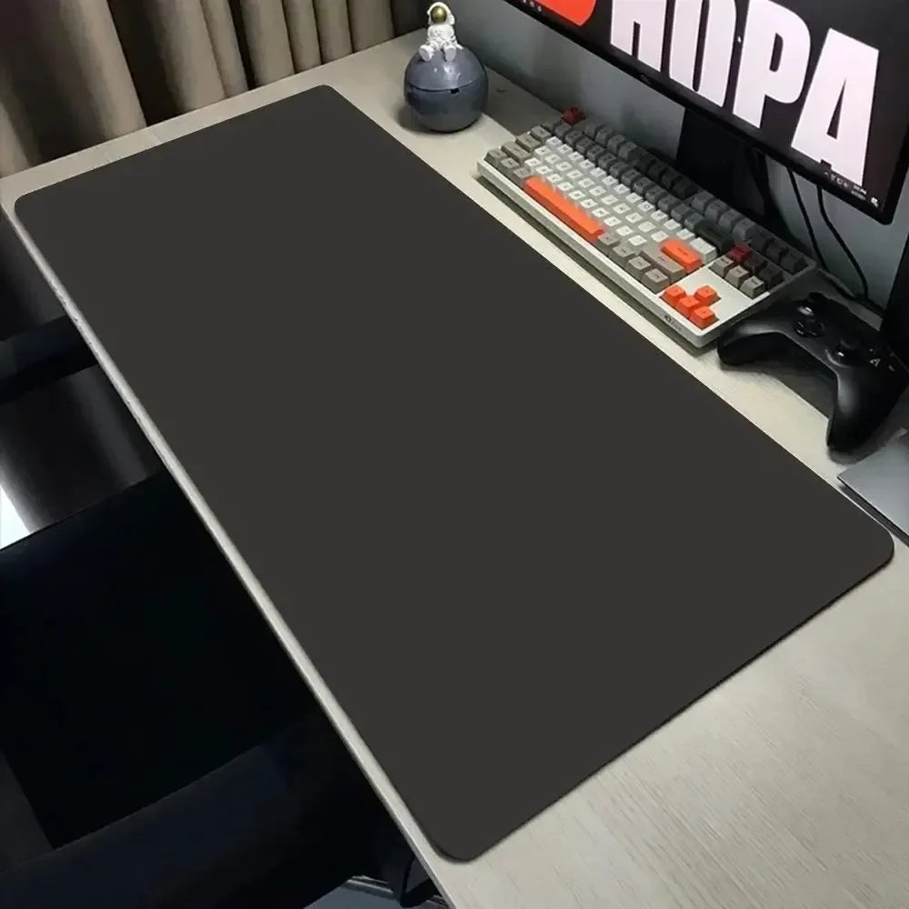 Large black desk mat on a desk with computer equipment.