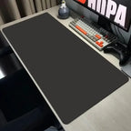 Large black desk mat on a desk with computer equipment.