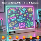 A neon-style LED magic board on a desk, glowing with colorful drawings and text including 'HAPPY MAGIC DAYS! GET CREATIVE! SUPER IDEAS BOARD.' The board is shown in a home office or store-like setting with books, pens, and ambient colored lighting.