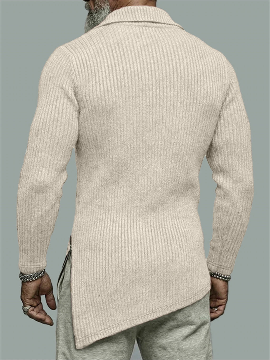 Man wearing a beige ribbed sweater against a gray background