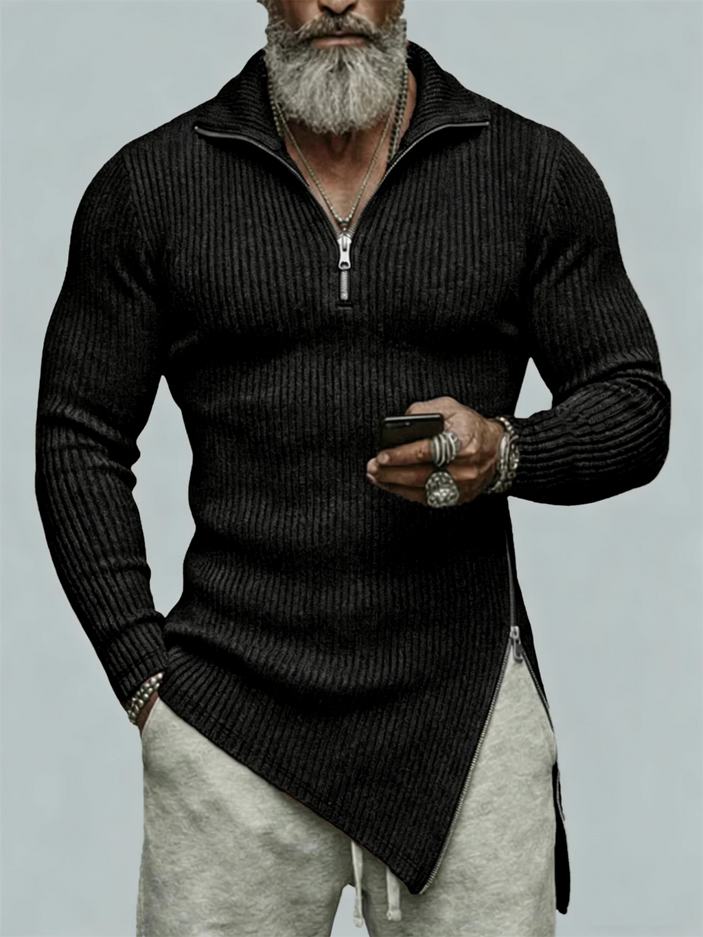 Man wearing a black sweater with a zipper, holding a phone, on a light gray background