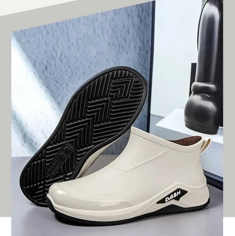 White rain boots with black soles on a light gray surface.