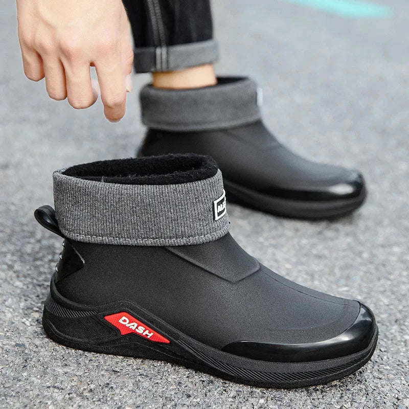 Black and gray ankle boots with a brand logo on a concrete surface