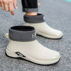 White rain boots with gray cuffs on a gray pavement background
